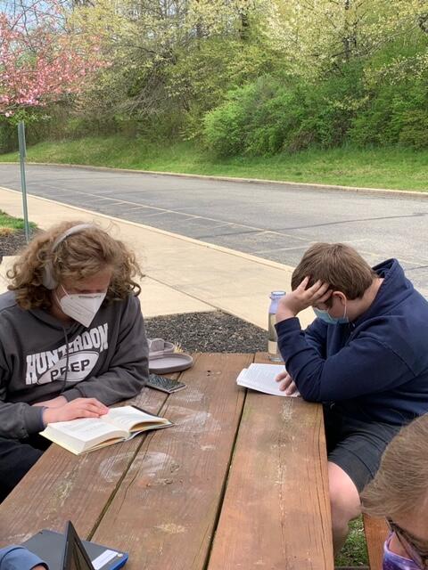 students sitting at a picnic table reading