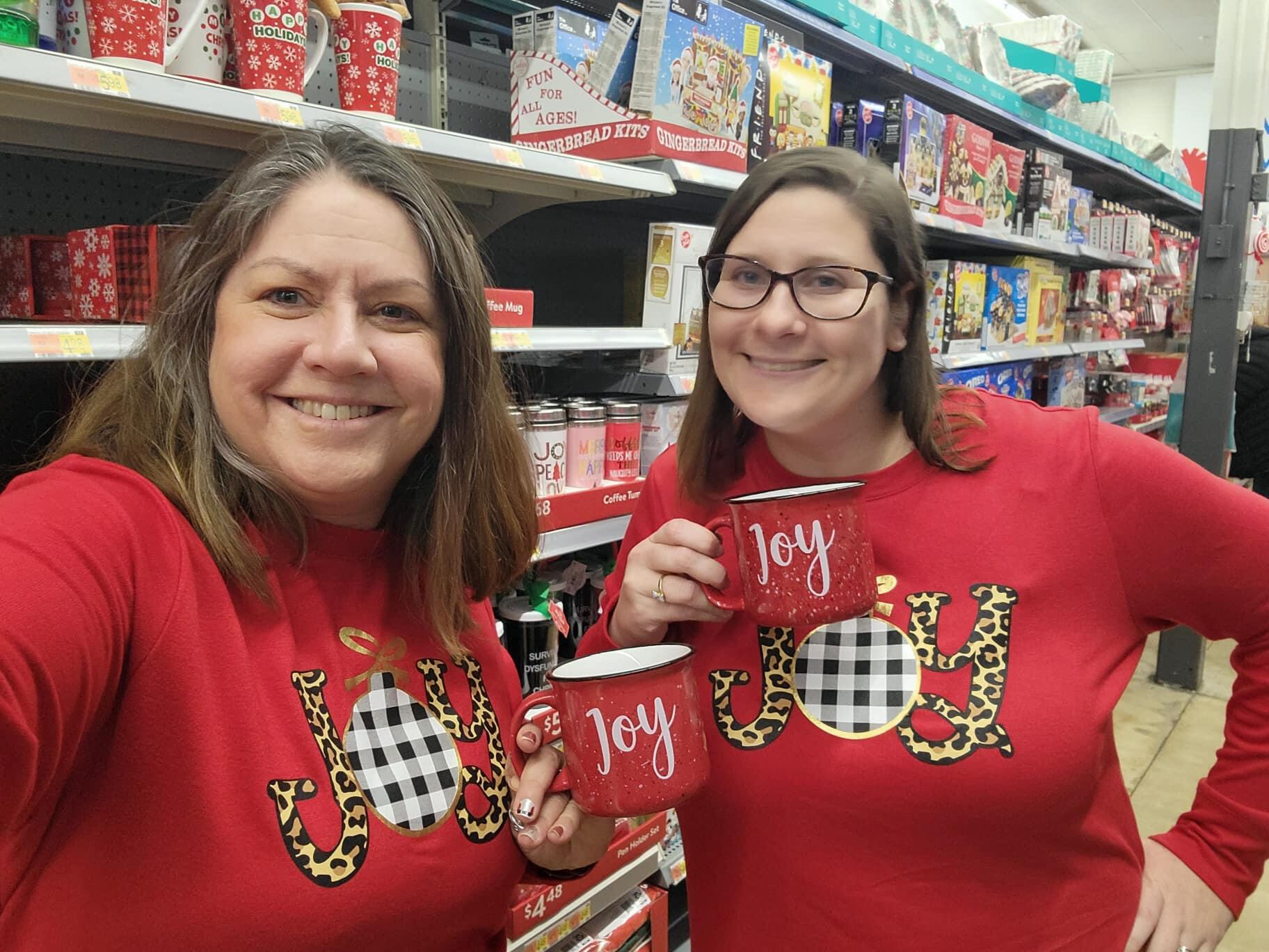 two teachers wearing matching shirts and holding matching holiday  mugs