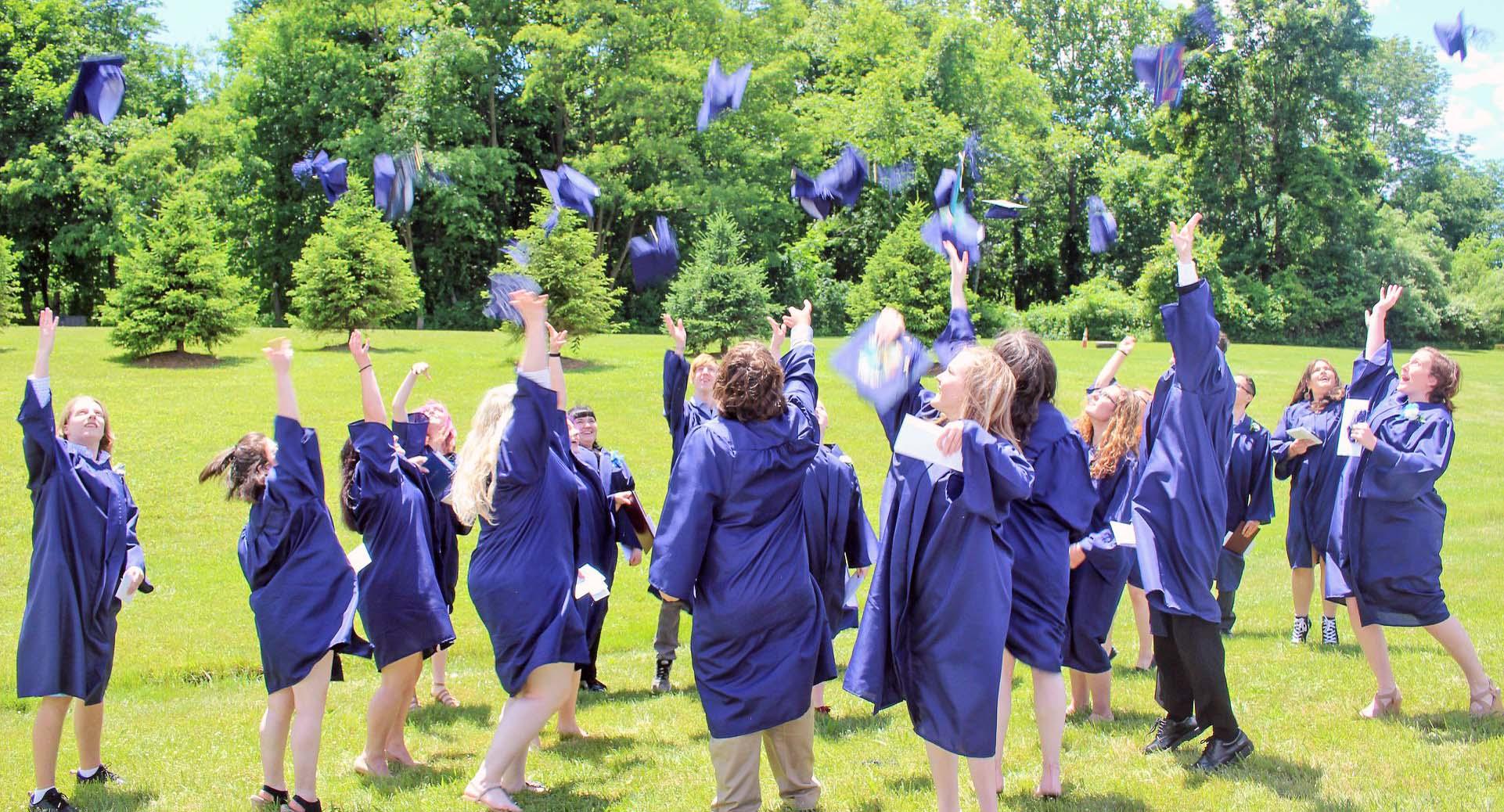A large group of Hunterdon Prep students in their graduation gowns throwing their caps into the air after the graduation ceremony. 